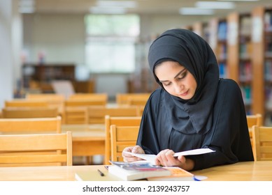 Muslim woman reading book in the library.