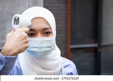 Muslim Woman Shop Keeper, Small Business Owner Do A Business Reopening Preparation Work By Wearing Proper Face Mask And Thermal Scan Her Fever Before Start Working