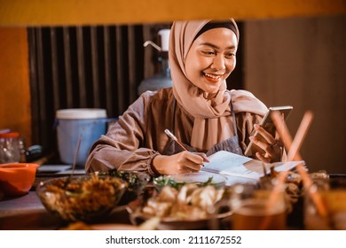 muslim woman small business seller write a note - Shutterstock ID 2111672552