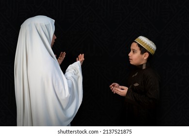 Muslim woman and son pilgrims in traditional clothes, praying at Kaaba in Makkah