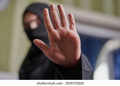 Eine muslimische Frau in traditioneller schwarzer Kleidung Nikab zeigen Stopp Hand Geste. Die Rolle der Frauen in der islamischen Welt. Häusliche Gewalt, Diskriminierung muslimischer Frauen. Beendigung der häuslichen Gewalt gegen Frauen