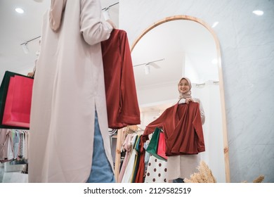 Muslim Woman Trying Dress In Mirror In Fitting Room