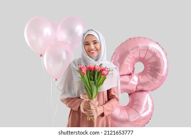 Muslim woman with tulips and balloons on light background. International Women's Day
