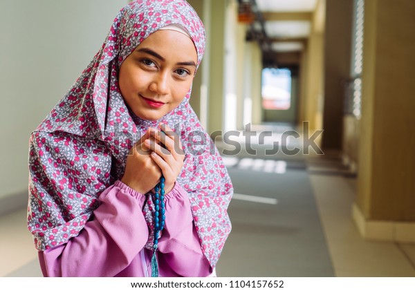 A Muslim\
woman wearing moslem clothes with hijab and rosary  praying in the\
mosque  Muslim woman raising hand\
pray