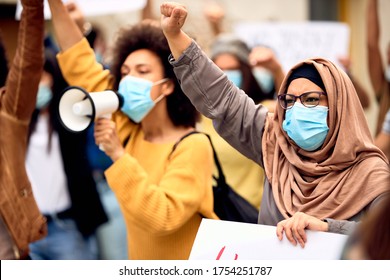 Muslim woman wearing protective face mask and supporting anti-racism movement with group of people on city streets.  - Shutterstock ID 1754251787