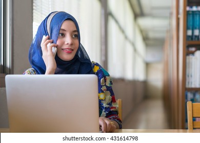 Muslim Woman Working With Computer And Talking Mobile Phone.