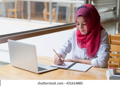 Muslim Woman Working With Computer And Writing Notebook.