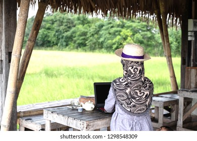 Muslim Woman Working With Laptop In Coffee Shop. Coffee Shop In Rice Field. Trip To Thailand.