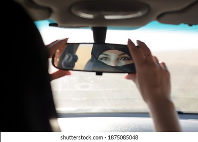 Muslim Woman's Eyes In Rearview Mirror Of A Car.