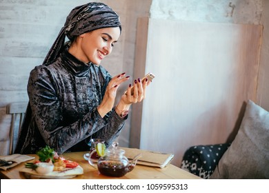 muslim women holding smartphonephone. thinking of good memories. serfing social media - Powered by Shutterstock