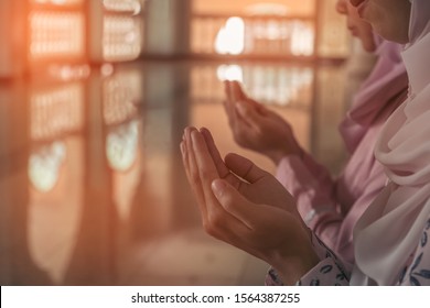 Muslim women wear a prayer veil in the mosque and have Arabic calligraphy on the window, meaning blessing to all Muslims, selective focus