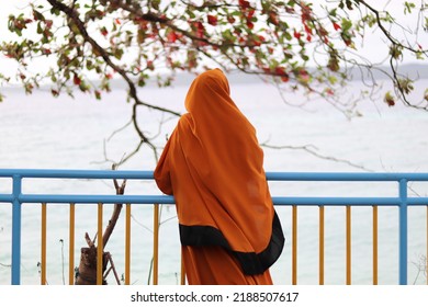 Muslim women who are looking at the sea view, the back view of a Muslim woman wearing a large orange hijab. - Powered by Shutterstock