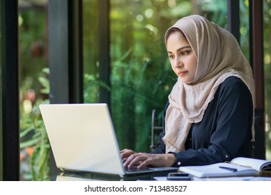 Muslim women working at a cafe and using computer.