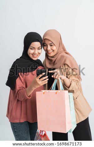 muslim young friend using smart phone and holding shopping bag together