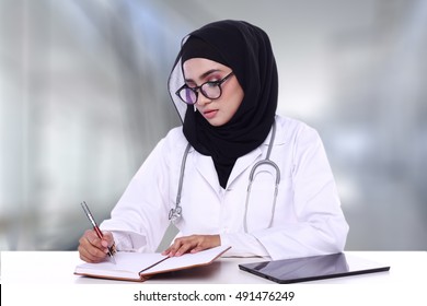  Muslimah Doctor Holding A Pen With Notebook And Ipad Isolated In Blur Background 