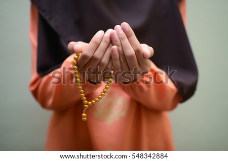 A Muslimah wearing traditional malay clothes with hijjab and rosary, praying in the mosque, Muslim woman raising hand pray. TONE images and background. shallow D.O.F Foto stock © 