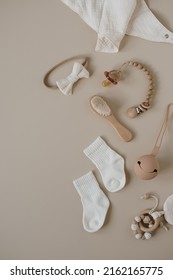Muslin bib, brush, pacifier, socks, bow, pacifier holder. Newborn baby accessories and toys set on neural beige background. Fashion Scandinavian newborn essentials. Flat lay, top view.