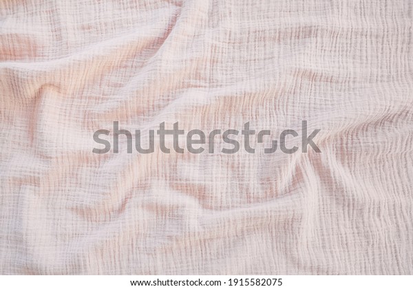 Muslin cloth texture background in neutral\
tones. Muslin cotton fabric of plain weave. Muslin is a soft,\
woven, 100-percent cotton multi-layer cloth popular for baby cloths\
and blankets.
