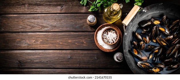 Mussels in a saucepan with parsley and spices. On a wooden background. High quality photo