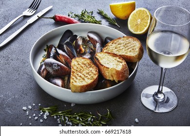 mussels in white wine sauce with glass of white wine  white bread toasts, decorated with hilly pepper, lemon and sea salt - Powered by Shutterstock