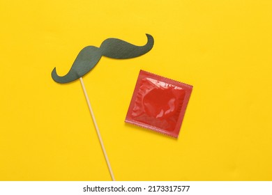 Mustache on stick, pack of condoms on yellow background