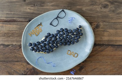 Mustache Shaped Cake With Blueberries And Decoration On Wooden Background. Copy Space. Father's Day. Masculine Concept.