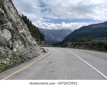 In Mustang, Nepal, a picturesque road meanders through lush greenery, flanked by verdant vegetation and terraced fields. Majestic mountains rise in the background, offering a stunning and tranquil vie - Powered by Shutterstock