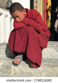 Mustang Nepal-May 2018: Portrait of pensive Tibetan boy. Young Novice sits on steps of monastic Buddhist school. Lo Manthang capital of Mustang Kingdom, Nepal. Reflections on life. Sad asian teenager.