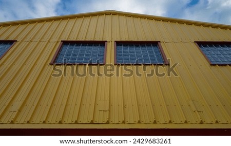 Mustard Gold and Brown Metal Building Wall with Windows Under an Arched Roof.