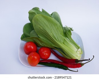 Mustard Greens, Tomatoes And Some Large Chilies Are Placed On A Plate Ready To Be Cooked For Vegetables