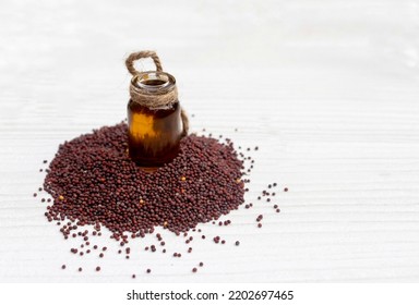 Mustard Oil In A Small Glass Jar With Black Mustard Seeds Isolated On White Wooden Background With Copy Space, Authentic Indian Condiment And Spices, Healthy Lifestyle Food