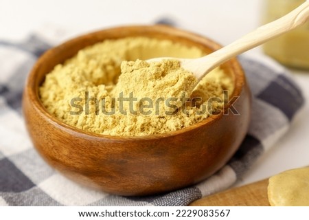 Mustard powder in wooden bowl. Mustards are plants of the genera Brassica and Sinapis.