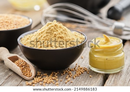 Mustard sauce jar and bowl of powdered mustard seeds. Scoop of whole mustard grain.