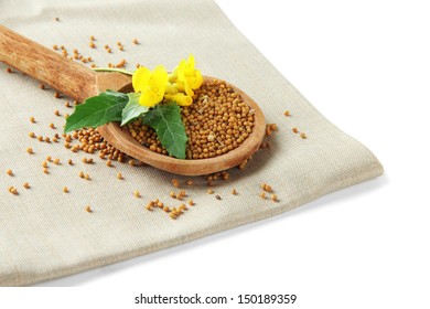 Mustard Seeds In Wooden Spoon With Mustard Flower Isolated On White