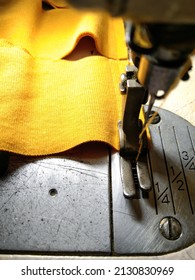 Mustard yellow cotton fabric is in the process of being sewn to make a t-shirt neck rib