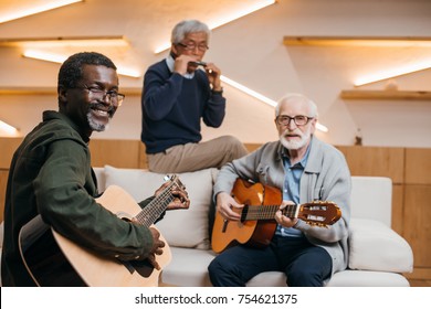 Mutiethnic Group Of Senior Friends Playing Music With Guitars And Harmonica