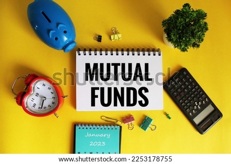 MUTUAL FUNDS word on Notebook with calculators and piggy bank, view from above. 