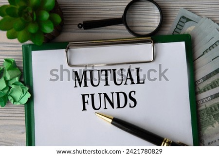 MUTUAL FUNDS - words on a white sheet against the background of banknotes, magnifying glass and cactus