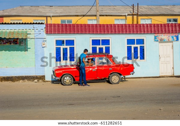 MUYNAK, UZBEKISTAN\
- SEPTEMBER 10: Guy speaking with the driver of old red colored car\
in Muynak. September\
2016
