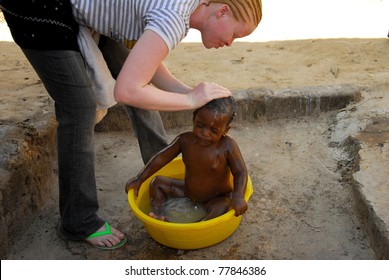 MWANZA,TANZANIA - FEBRUARY 8: African Albino Mother Bathing Her Unidentified Child,on February 8,2010 In Mwanza,Tanzania.In Tanzania The Frequency Of Albinism Has Been Estimated To Be Approximately 1 In 2500