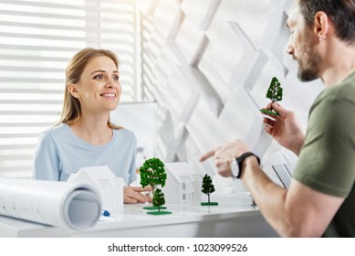 My Favourite Work. Beautiful Content Fair-haired Young Woman Smiling And Working With Her Colleague On An Eco-friendly Project While Sitting At The Table