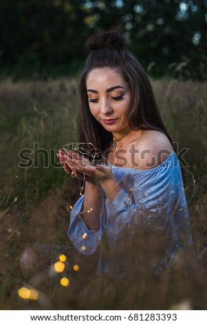 My friend looks deeply towards a string of fairy lights during a summer photoshoot in a meadow near Liverpool.