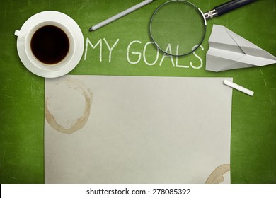 My goals concept on green full frame blank blackboard with coffee cup. empty paper and magnifying glass