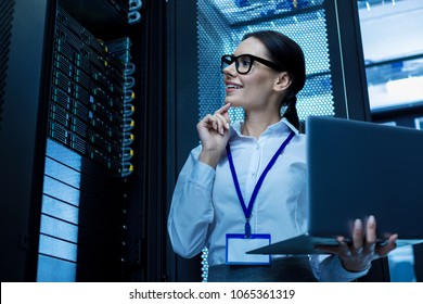 My good day. Alert beautiful woman working in a server cabinet and holding her laptop