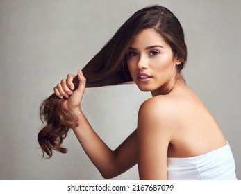 My hair regime has made my hair stronger. Studio shot of a young beautiful woman with long gorgeous hair posing against a grey background.