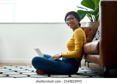 I am in my happy place. Cropped shot of an attractive young woman sitting crosslegged on the floor and using her laptop at home.