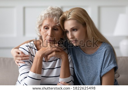 My heart warms to you, dear mommy. Sad young adult woman grown up daughter or grandkid sitting on sofa hugging desperate, grieving, frustrated elderly mom or grandma having problems with mental health