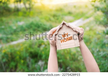 My home background. House construction, home for the family. Concept with kid's hands holding little wooden house with text My home. 