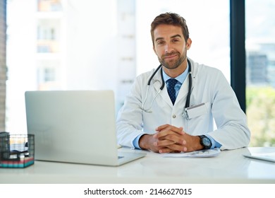 My Job Is My Calling. Portrait Of A Happy Doctor Using His Laptop While Sitting At His Desk.