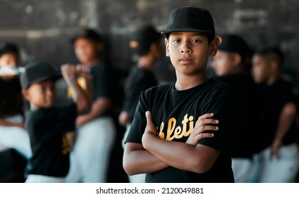 My Mom Says That Im Pretty Good. Portrait Of A Young Baseball Player Standing With His Arms Crossed With His Teammates Standing In The Background.